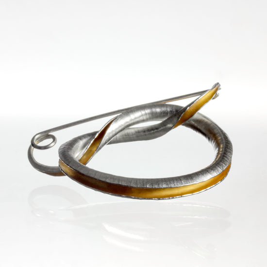 Handmade anticlastic silver knot brooch with integral pin and catch, part gold plated on inside surface with yellow gold. Hammered texture, burnished edges and satin-matte finish.