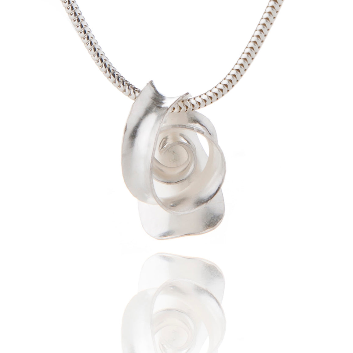A small spiral pendant handmade from recycled sterling silver. A ribbon of metal loops and twists over from the base and forms a spiral.