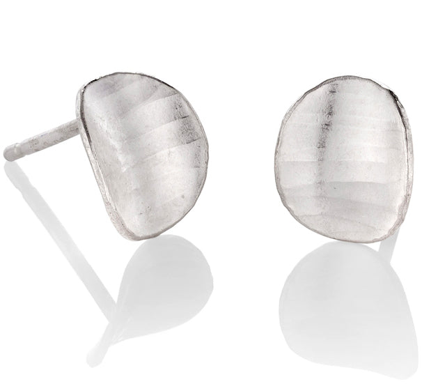 A pair of oval studs, variations of the square silver earrings, with a subtle curve, a hammered texture and burnished edges.