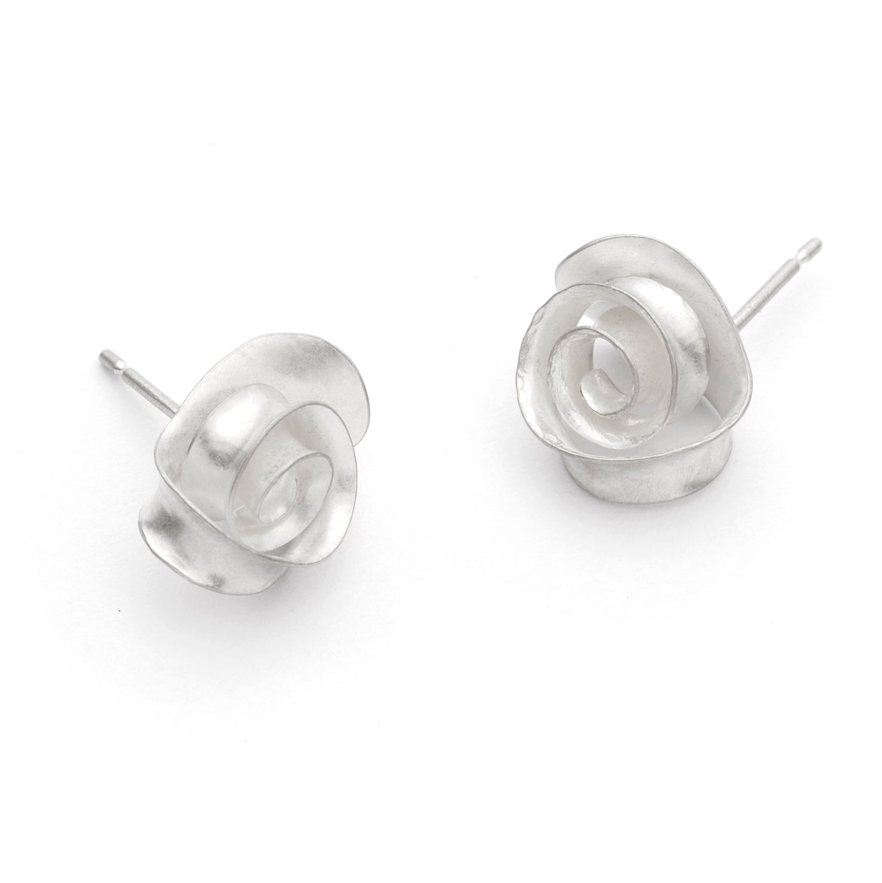 A peir of delicate swirl earrings made from recycled sterling silver. Each stud is made from a single piece of silver, with a spiralloing ribbon of metal twisting so that it lies flat against a curved backing. A different view.