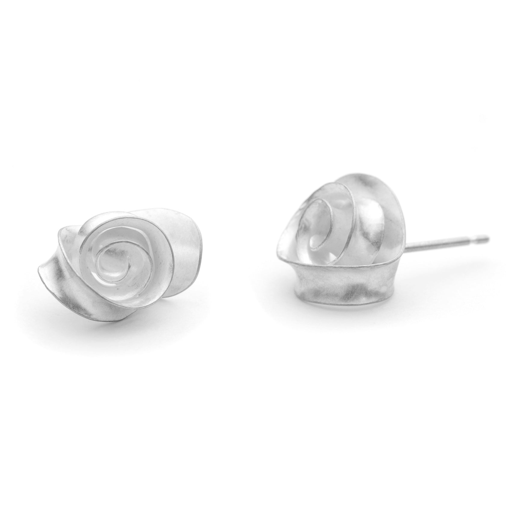 A peir of delicate swirl earrings made from recycled sterling silver. Each stud is made from a single piece of silver, with a spiralloing ribbon of metal twisting so that it lies flat against a curved backing. A different view, showing one stud from the front and the other from the side.