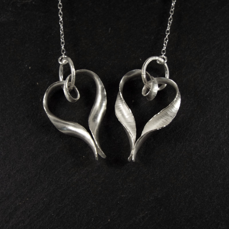 The Ripple silver heart drop earrings in the Chain variant, showing both the front and the back. The front view has a hammered texture and the back is smooth.