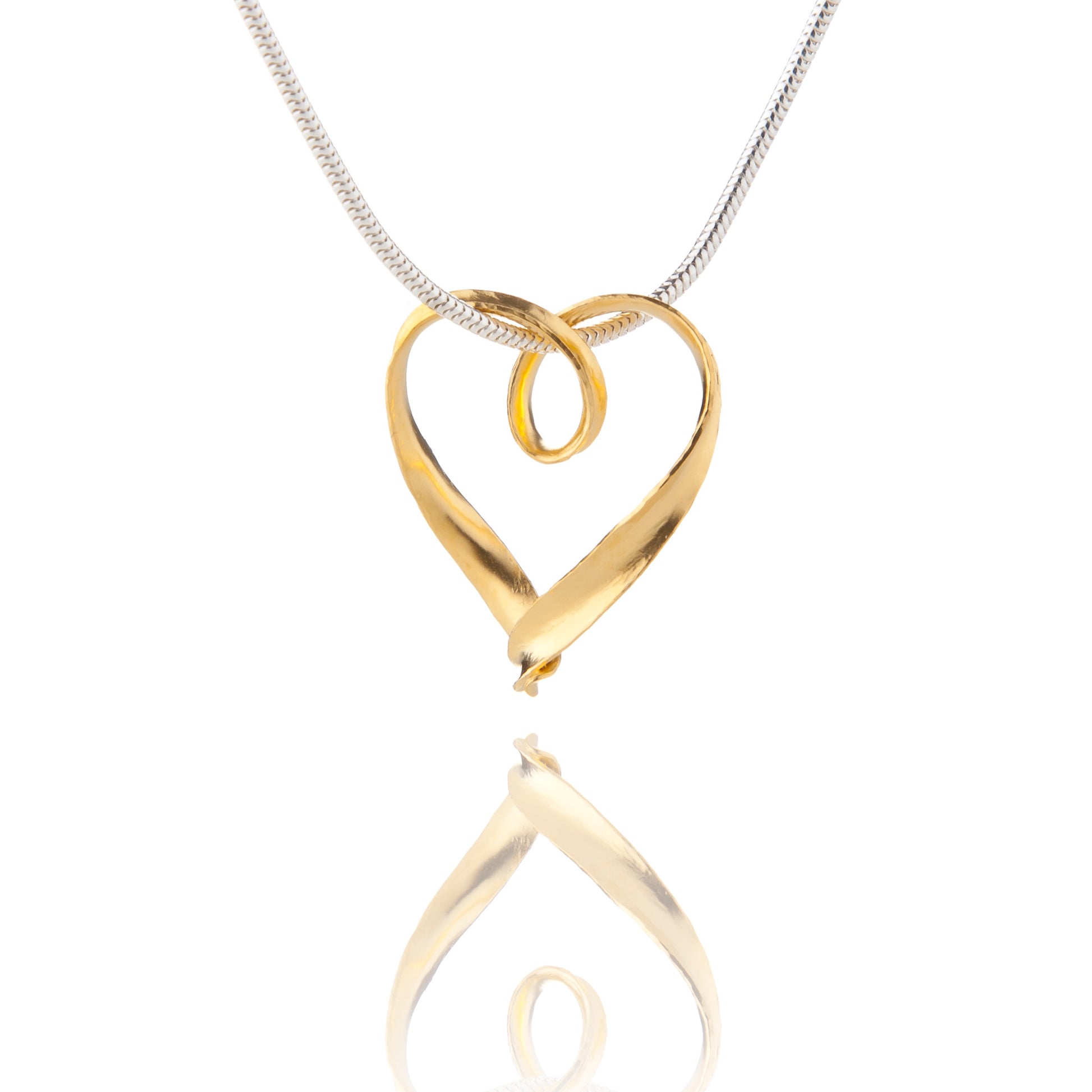 A simple silver heart pendant formed from a continuous strip of recycled silver, thickly plated with yellow gold, hanging from a silver snake chain which passes through a loop in the heart.