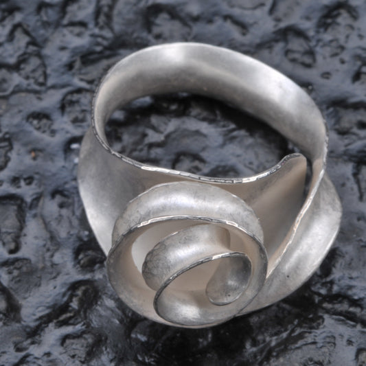 Scroll ring seen from the front and above against a dark, textured, glossy background